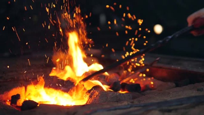 一个有乌合之众的人正在篝火中混合煤