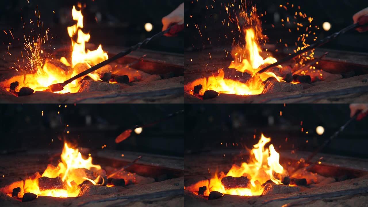 一个有乌合之众的人正在篝火中混合煤