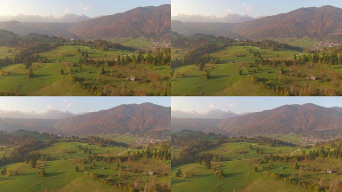 色彩缤纷的山和绿色牧场下的乡村小镇的空中风景拍摄