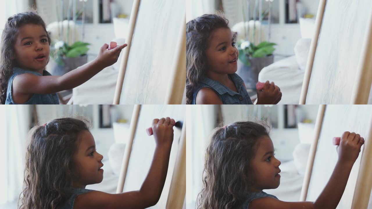 年轻的西班牙裔女孩在家用粉色粉笔在黑板上画画，特写，侧视图