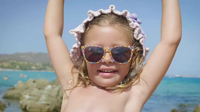 美丽的小女孩在海上玩耍的肖像，在巴拿马可爱的微笑，防晒霜，海蓝色的水和岩石的背景。