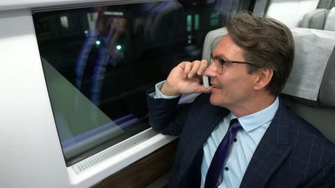 英俊的商人在火车上通勤，一边打电话一边看着窗户