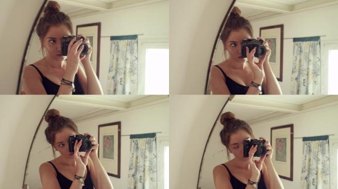 手持相机的年轻女孩站在镜子前，自拍
