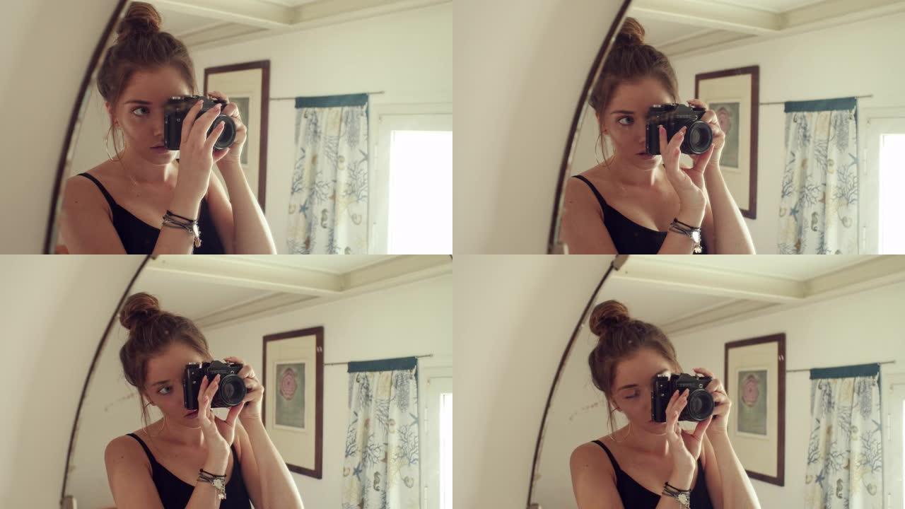 手持相机的年轻女孩站在镜子前，自拍