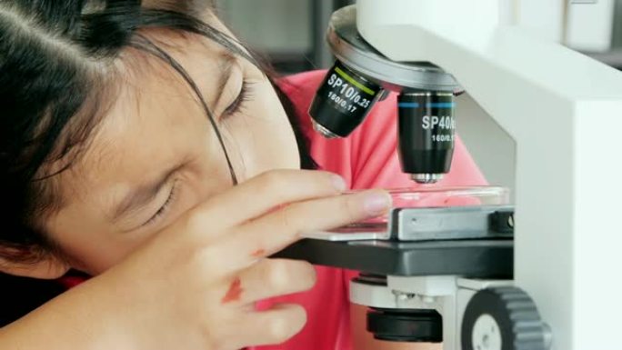 有趣的小女孩在实验室里做实验和显微镜。科学与教育。孩子生命中的一天。教育主题