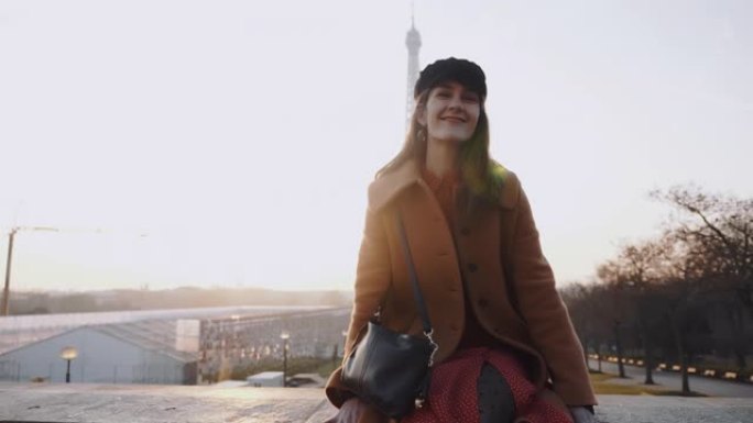 快乐美丽的黑发旅游女人在秋季巴黎度假慢动作中，在令人惊叹的埃菲尔铁塔景观中兴奋地摆姿势。