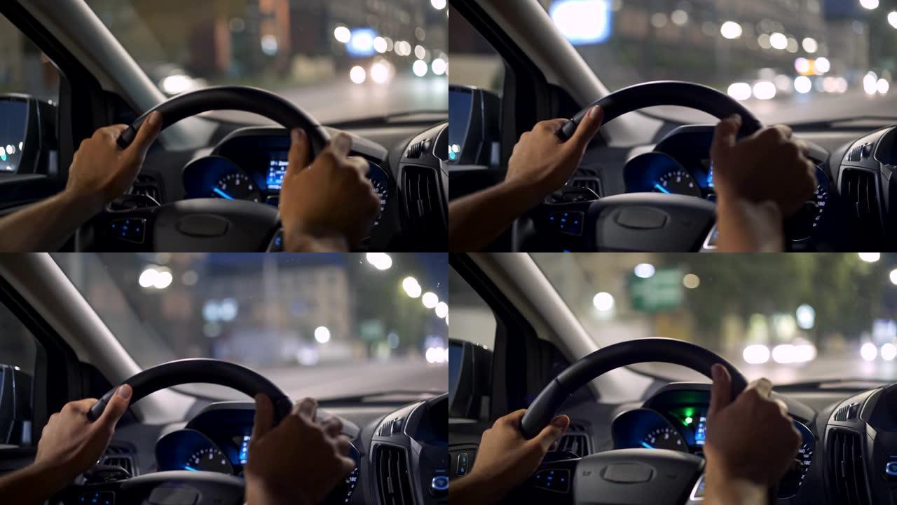 在夜城开车的人。男性手握方向盘。迎面而来的交通与美丽的bokeh不在焦点上。4K