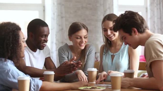 千禧一代不同种族的朋友坐在桌子旁组装拼图游戏