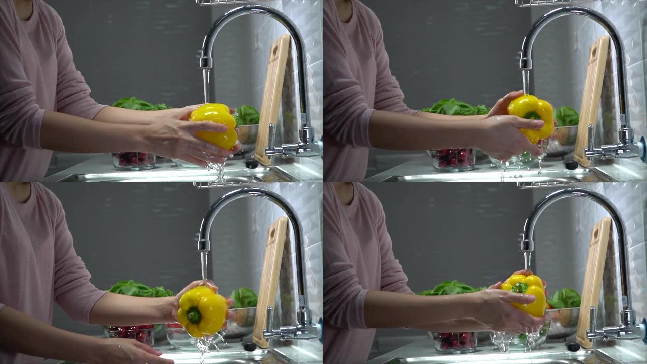 女人洗菜妈妈清洗黄色菜椒流动的水厨房洗菜