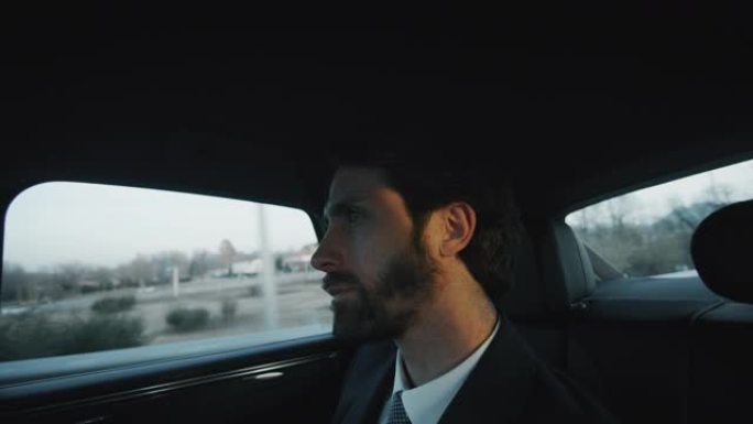 慢镜头近距离观察英俊的商人在一个现代汽车旅行期间，一个司机在城市中心的白天