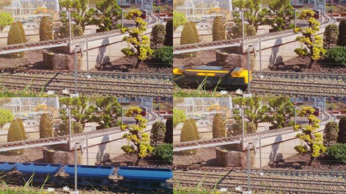 带有玩具货运列车的微型铁路在桥下通过。用轨道、风力涡轮机和树木缩放表示。