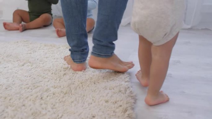 无法识别的幼儿学习与地毯上的女人一起走路