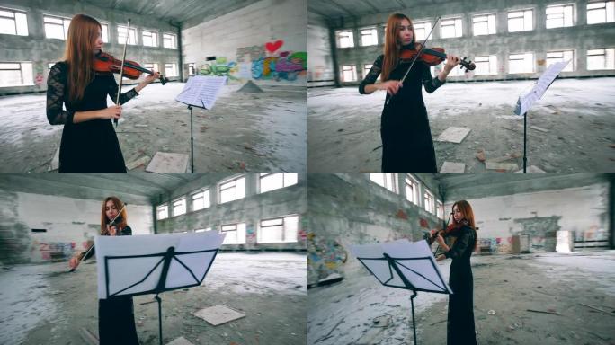 专业小提琴手在废弃建筑的大房间里按音符演奏。