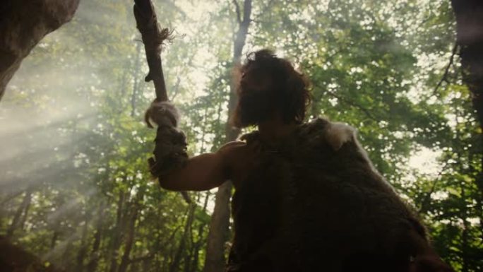 穿着动物皮的原始穴居人手持石矛在史前森林周围望去，准备猎杀动物猎物。石器时代的尼安德特人去丛林打猎。