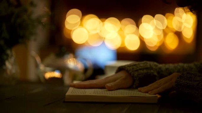 女人晚上在家看书翻页。茶壶和茶杯。美丽的圆形黄色博克。UHD滑块镜头