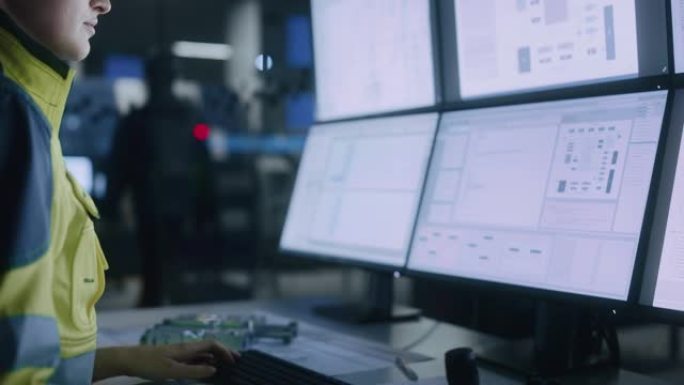 工业4.0现代工厂: 女性设施操作员控制车间生产线，使用计算机，屏幕显示机器操作过程、控制器、机械蓝