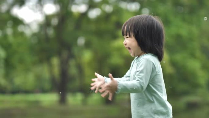 亚洲妈妈妈妈和孩子一起吹泡泡，吹肥皂泡，在公园里玩得开心