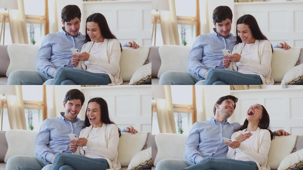 开朗的年轻夫妇在手机上看有趣的视频很开心