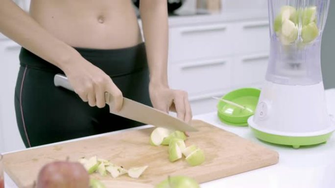 运动型亚洲女性在厨房准备制作苹果汁的配料，穿着运动服的女性在家中使用有机水果大量营养制作苹果汁。健康