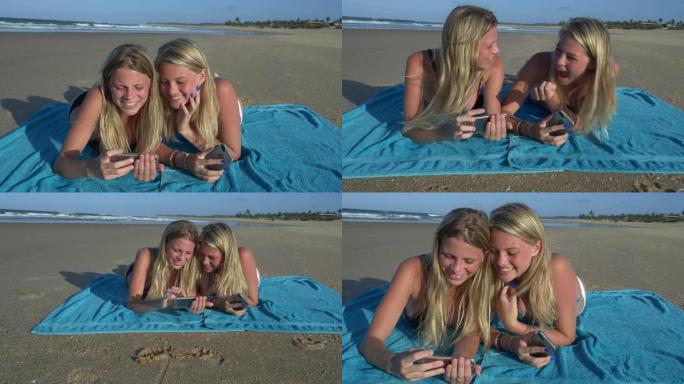 南非海滩上，两个美丽的年轻女子躺在毛巾上，在手机上笑着分享笑话的4k前视图