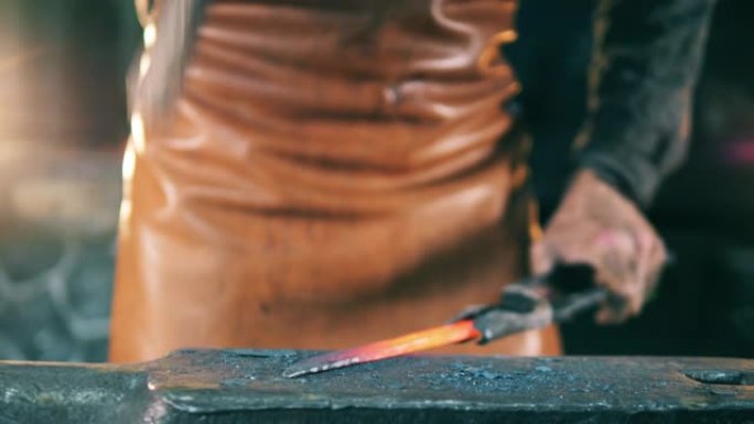 人用铁砧上的锤子塑造一把热刀。