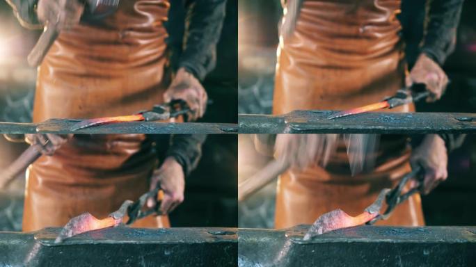 人用铁砧上的锤子塑造一把热刀。