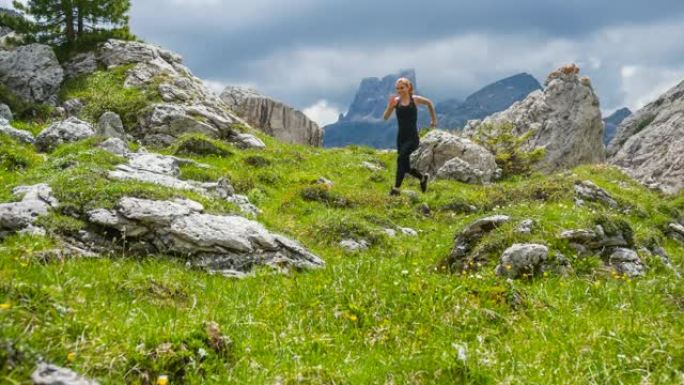 快乐女运动员在山腰的绿色草地上跑步
