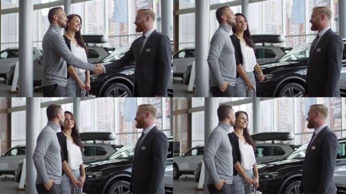 卖家在汽车经销商中与欢乐的顾客握手