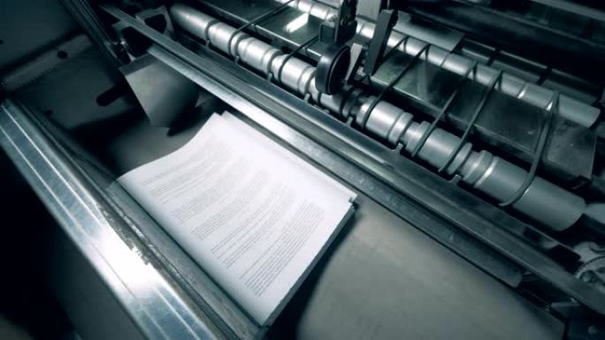 带有文本的纸质页面正在机械发行。印刷厂设备。