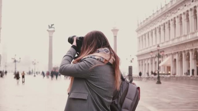 美丽的女性旅行博客作者与相机拍摄令人惊叹的意大利威尼斯古老古董城广场慢动作