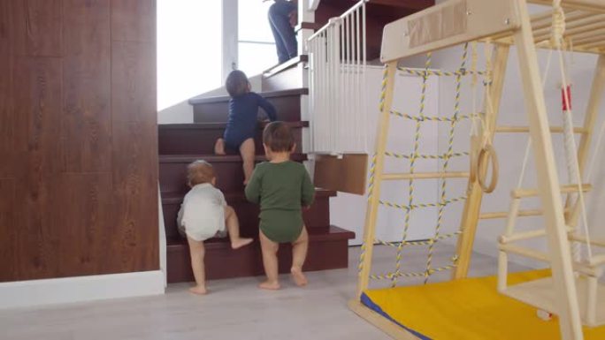 蹒跚学步的三胞胎爬上楼梯朝妈妈走去