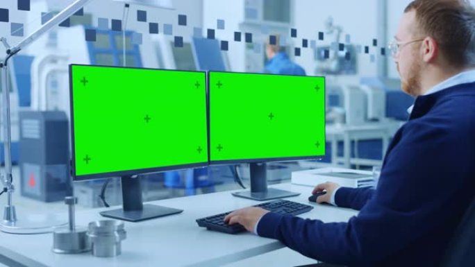 在个人计算机上工作的工业工程师，两个监视器屏幕是模型，绿色屏幕，色度键显示。拥有高科技机械的现代化工