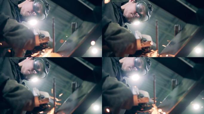 男人在工厂工作时使用研磨机。许多磨碎的火花。