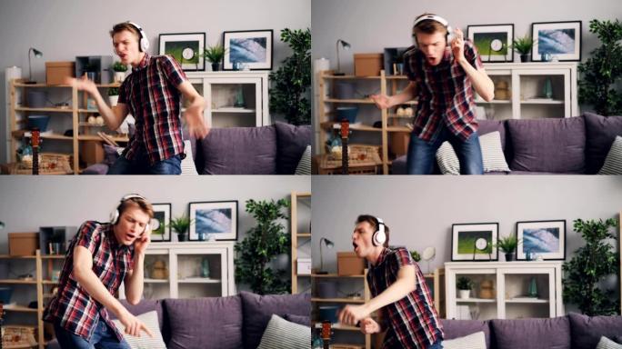 英俊的男人在公寓里玩得很开心，戴着耳机跳舞和唱歌听音乐
