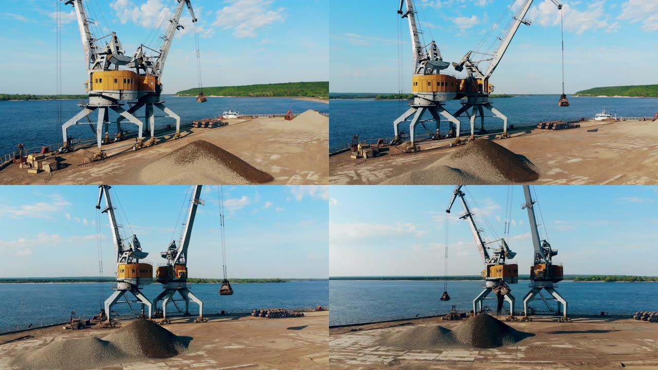 用两台起重机在码头卸下碎石。
