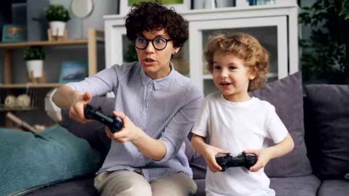 小男孩和兴奋的妈妈在家里拿着操纵杆玩电子游戏