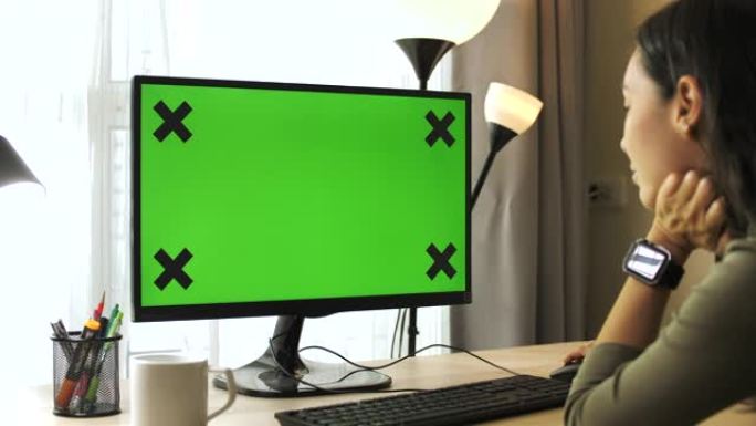 亚洲妇女在家中使用带有绿屏的计算机