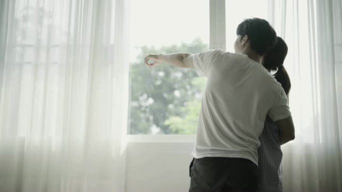 年轻夫妇早上在窗前拥抱和交谈。