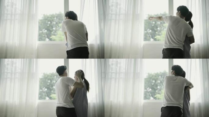 年轻夫妇早上在窗前拥抱和交谈。