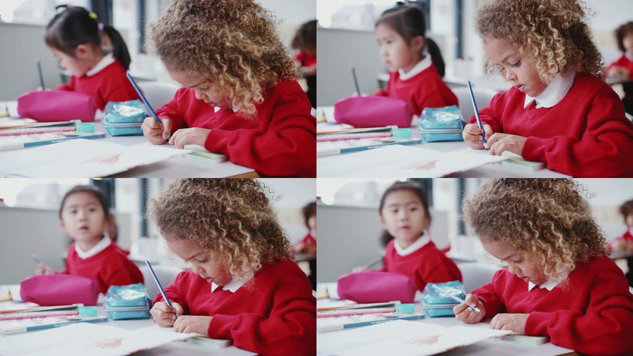 混血女学生在幼儿教室的桌子上画画的特写镜头，专注于前景