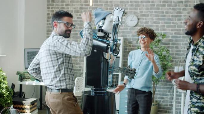 快乐的机器人工程师在办公室与智能的类人机器人共舞