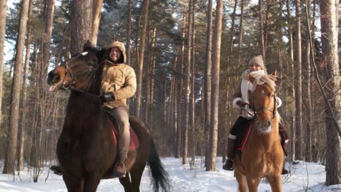 幸福的夫妇在冬季公园骑马