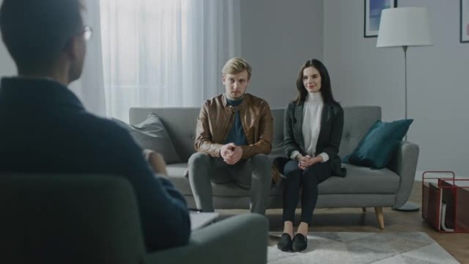 年轻夫妇与心理治疗师咨询。治疗师的后视图: 年轻人坐在分析师沙发上，讨论心理创伤，人际关系问题和痛苦