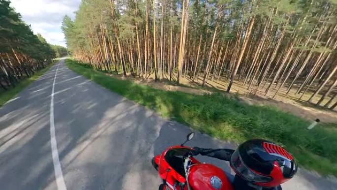 森林路和一个驾驶摩托车的人。路上的摩托车。