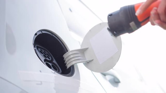环保女性将电动汽车连接到电动汽车充电站