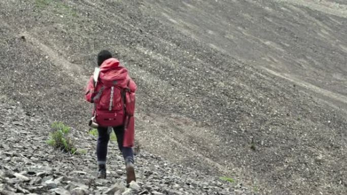 女性背包客在山上行走的后视图