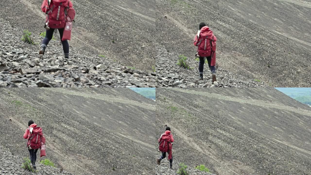 女性背包客在山上行走的后视图