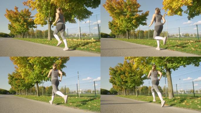 复制空间: 女人在风景秀丽的秋天彩色大道上慢跑的电影镜头。