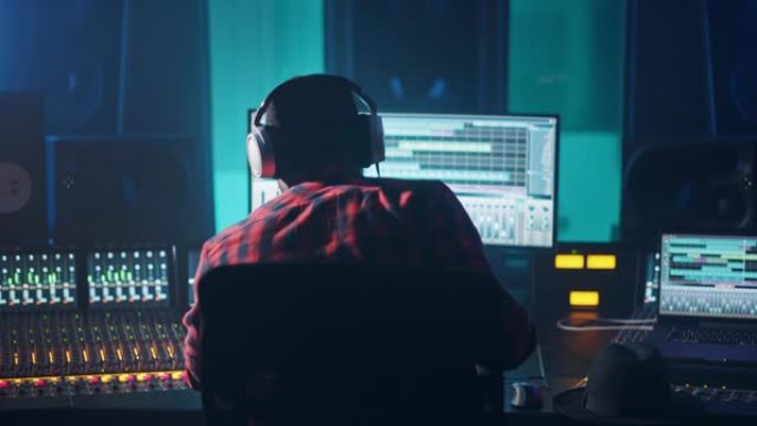 音乐录音室的艺术家，音乐家，音频制作人，使用带有计算机屏幕的控制台，显示带有歌曲播放的软件UI。举手