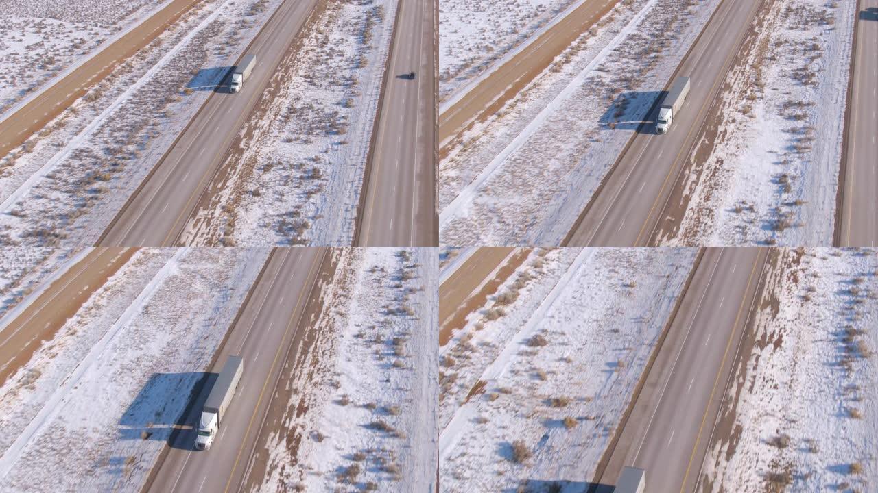 无人机: 白色卡车将货物运送到风景秀丽的高速公路上，穿越雪域的沙漠